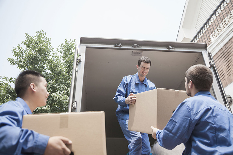 Movers unloading a moving van and passing a cardboard box