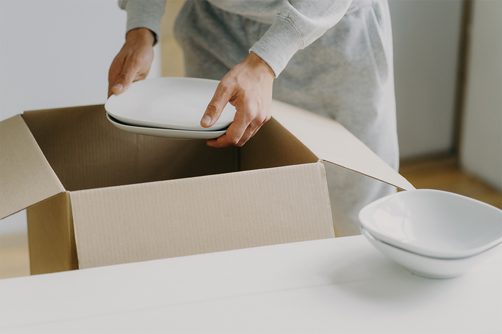 Man is Packing Ceramic Plates in a Box